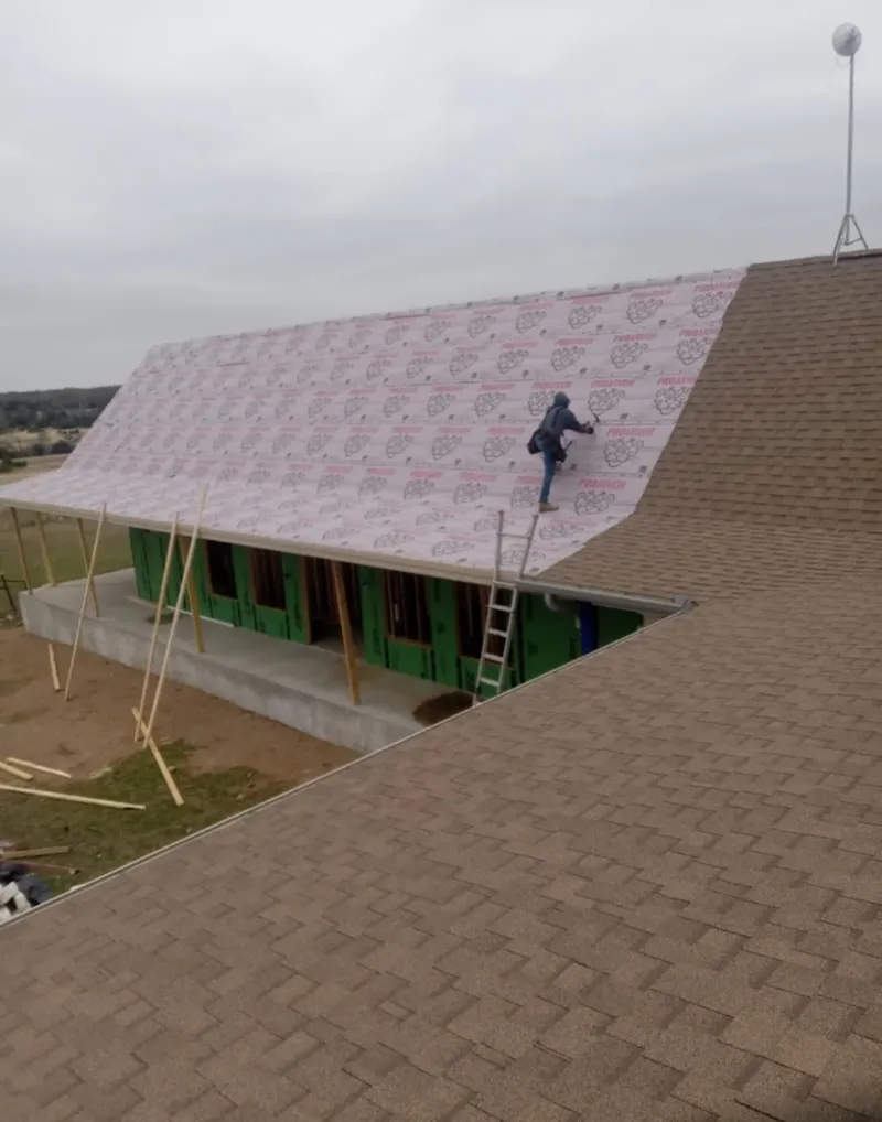 Worker preparing underlayment for a metal roof installation in Dover